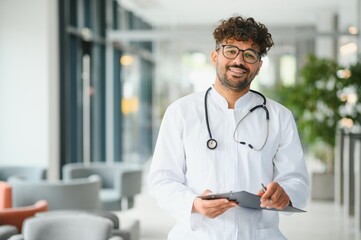 Smiling arab doctor holding medical chart in hospital lobby