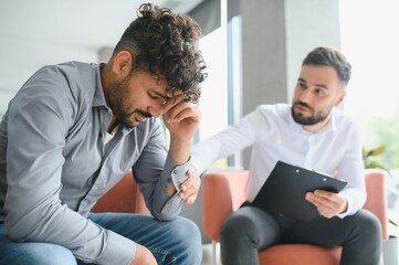 Obraz premium Psychologist comforting upset arab man during therapy session