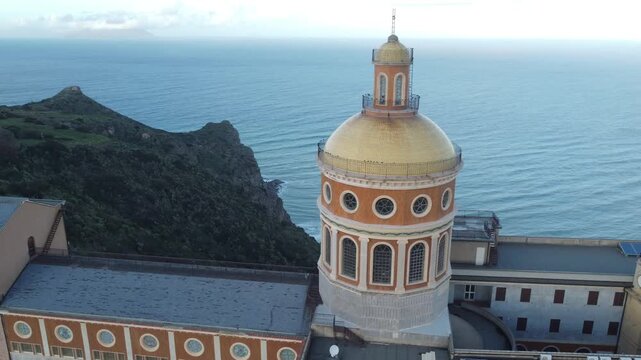 Cinematic drone footage of Basilica Santuario Maria del Tindari, Italy, capturing the historic church on the hill with the sparkling Mediterranean Sea in the background under clear summer skies
