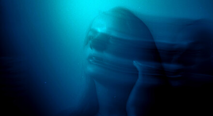 Dreamy moody cinematic portrait of a brunette woman with blue-aqua glow and long exposure