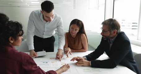 Diverse business team analyzing marketing reports, pointing at diagrams - Powered by Adobe