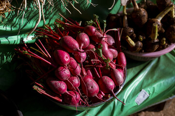 Fresh red radish overflowing from bowl at vibrant market stall, offering healthy and delicious...