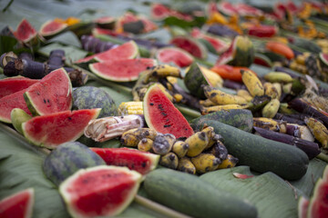 Large pile of diverse organic food waste featuring various spoiled fruit and vegetable items, including watermelon slices, corn, and banana. Abundant produce from market now undergoes sad decay