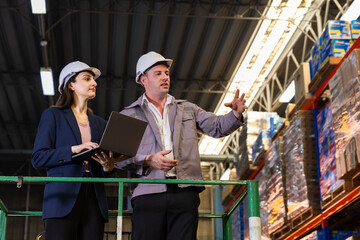 Warehouse supervisors collaborating with laptop, logistics business leaders in safety helmet analyzing inventory and planning teamwork, supply chain industry professionals ensuring delivery efficiency