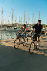 Young Couple Cycling to Yacht at Marina
