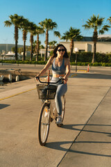Young Woman Cycling to Yacht at Marina