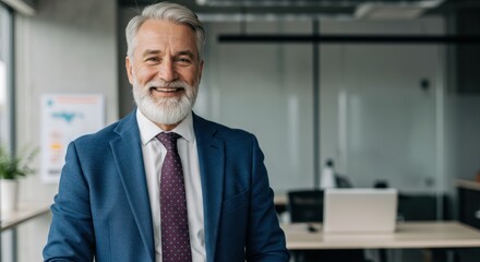 Smiling mature man in suit stands in modern office with blurred background.