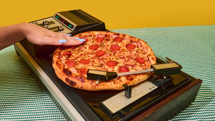 Closeup of hand pressing pizza onto spinning vinyl turntable in retro concept. Idea of psychology and emotions, social media and digital content, retro technology, design and creative expression.