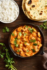 Chicken tikka masala curry in cast iron pan on wooden table