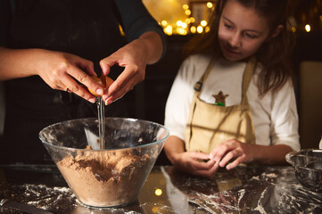 Family Baking Night: Adults Cracking Eggs While Child Watches Over Gingerbread Dough