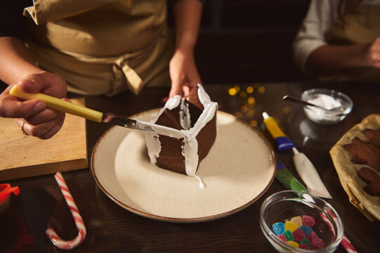 Family Decorating Chocolate Cake With White Icing For Christmas Celebration At Home - Powered by Adobe