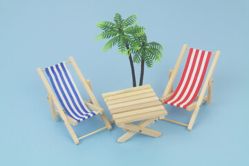 Blue and red beach chairs with wooden table on blue background. Copy space for text. Travel and vacation concept.