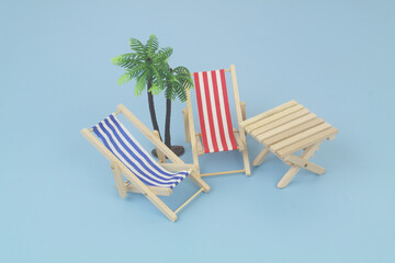 Blue and red beach chairs with wooden table on blue background. Copy space for text. Travel and vacation concept.