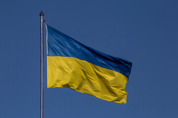 Ukrainian flag on flagpole against clear blue sky