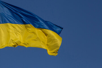 waved Ukrainian flag against clear blue sky