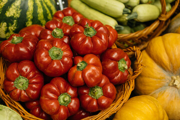 A vibrant array of vegetables like peppers, zucchini, and squash in a rustic basket at a lively farmers market