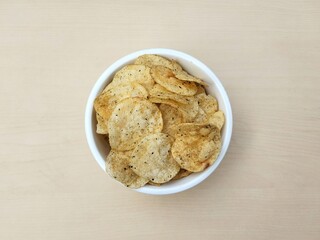 Seaweed flavored potato chips in white bowl on wooden table background. Flat lay