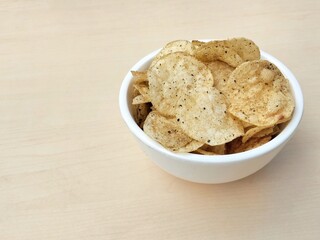 Seaweed flavored potato chips in white bowl on wooden table background. Flat lay, Copy space 