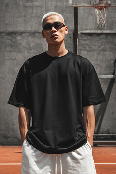 A  male model wearing a black over-sized t-shirt with street style. A product shot for fashion and apparel. best use for mockup.