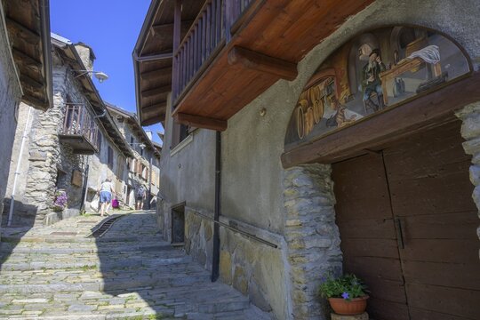 Pictures on the house walls characterise the narrow streets with old houses in the village, Usseaux, metropolitan city of Turin, Italy