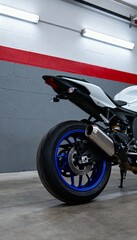 Fototapeta premium Close-up of a white and black motorcycle with blue rim in a modern garage