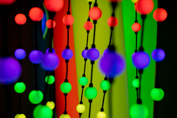 Colorful decorative lights hang against a blue background. The lights are round and vary in color,...