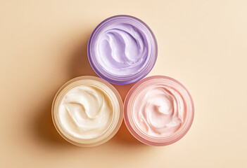 Three Jars of Face Cream – One Purple and White, Two Light Pink on Beige Background.