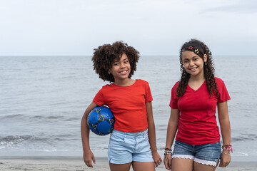Girls smiling on beach playing with soccer ball