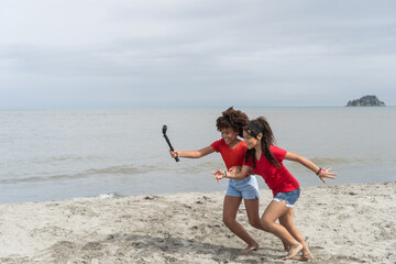 Fototapeta premium Girls vlogging vacation experiences on beach using action camera