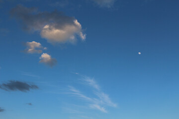 Blue evening  sky background with moon and clouds illuminated by sun (Baden, Germany)
