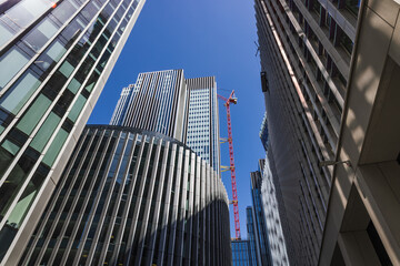 Modern glass skyscrapers and red crane in business district, low angle urban view