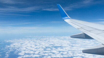 Beautiful landscape view trough window of airplane and cloudless sundown sky behind window of aircraft during flight. blue sky. Flying in the sky and the sea of clouds.