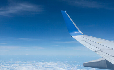 Beautiful landscape view trough window of airplane and cloudless sundown sky behind window of aircraft during flight. blue sky. Flying in the sky and the sea of clouds.