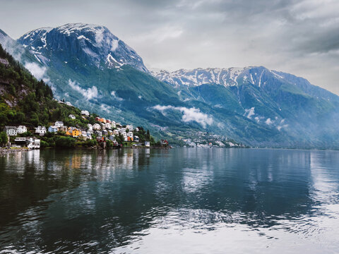 Odda town in Norway - traditional houses and fjord with foggy mountains in Vestland, beautiful travel destination Scandinavian landmarks summer scenic view