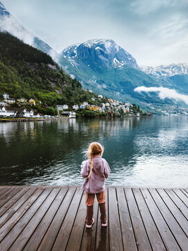 Child traveling in Norway sightseeing Odda town and fjord view family vacations kid girl tourist standing on wooden bridge, explore Scandinavian landmarks