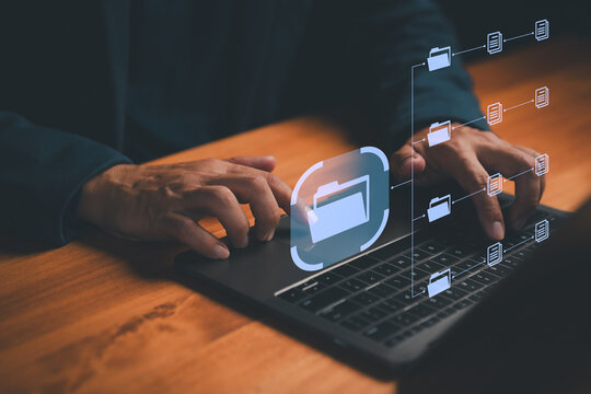 Close-up of hands using laptop with virtual digital folders and documents interface, symbolizing data management, file storage, cloud computing, organization, and modern information technology. - Powered by Adobe