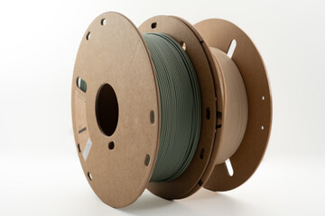 Rolls of muted green and beige PLA 3d printer filament on environmental friendly cardboard roll...