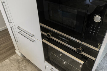 Close-up of modern kitchen appliances. Features a black microwave and oven combo with sleek...