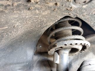 Detailed view of a car suspension spring under a vehicle