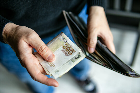 Close-up of hands holding a 200 Polish zloty banknote and wallet. Concept of finance, cash payment, budgeting