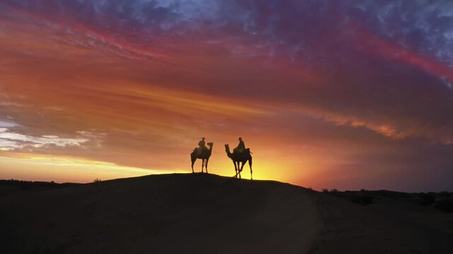 Camel riders. Silhouetted camel riders on a desert sand dune at sunsset . The Thar Desert is an arid region in of Rajasthan in north western part of of India