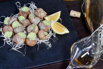 stuffed mussels on black slate with lemon on table with glass of wine