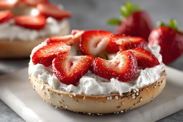A bagel with cream cheese and fresh strawberries is ready to eat.