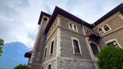 Walking around the beautiful Cantacuzino Castle, Bu?teni, Romania on a rainy day. Low angle view. Hazy mountains at backdrop.