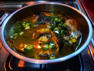 Silver catfish in yellow soup cooked in a stainless steel bowl.