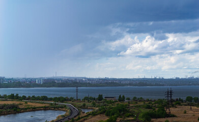 Rainstorm over lake and industrial cityscape