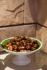 Close-up of fresh dried dates (kurma) served on a banana leaf in a ceramic dish — natural sweet snack commonly served during Ramadan and festive occasions.
