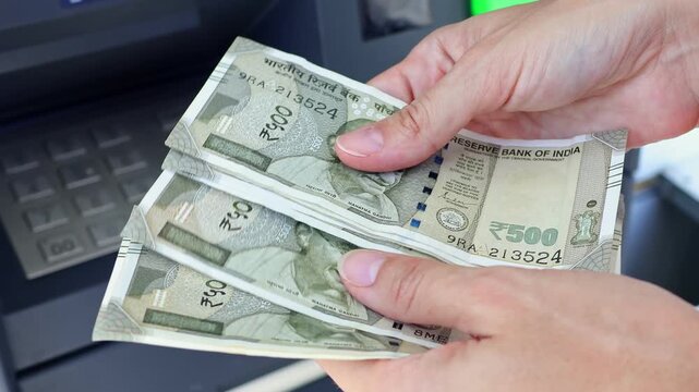 Close up view of woman hands counting Indian rupee banknotes (INR) in ATM. Concept of saving money for retirement, cash settlement, financial goals, success, literacy and income planning in India.