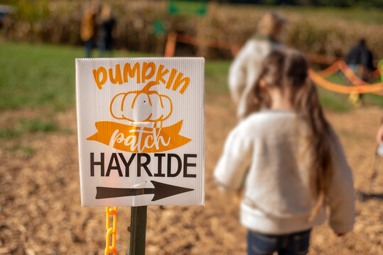 Pumpkin patch hayride sign isolated with cornfield and children lining up in the background