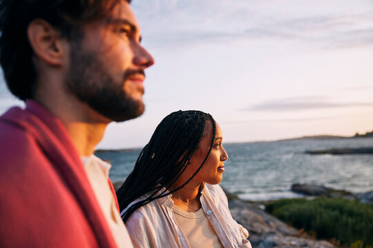 Woman spending leisure time with male friend looking at view near sea